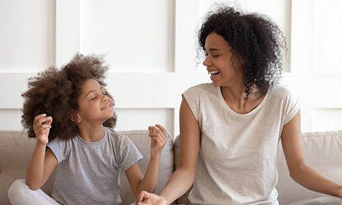 Woman and girl sitting on couch laughing